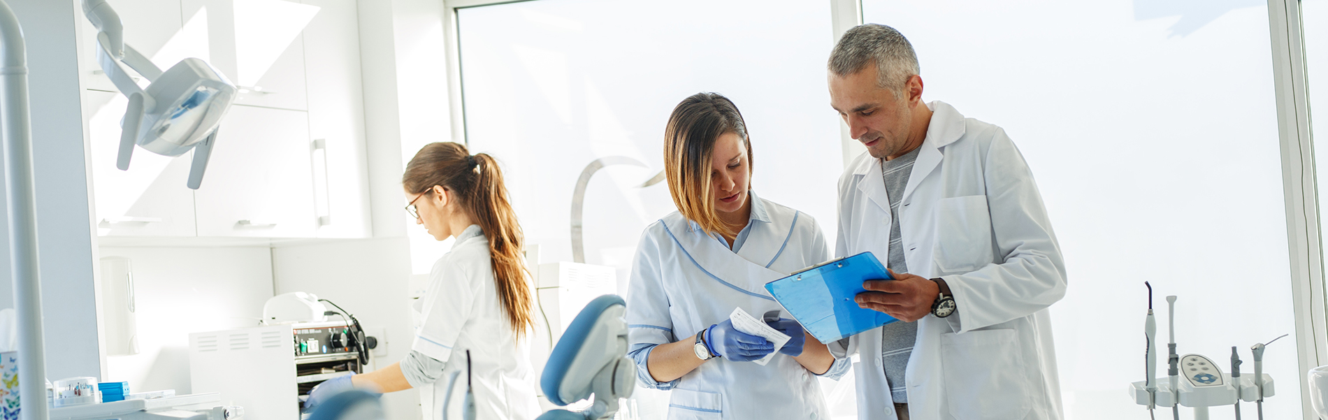 The image shows a modern dental clinic interior with various pieces of equipment, including a dental chair and an X-ray machine.