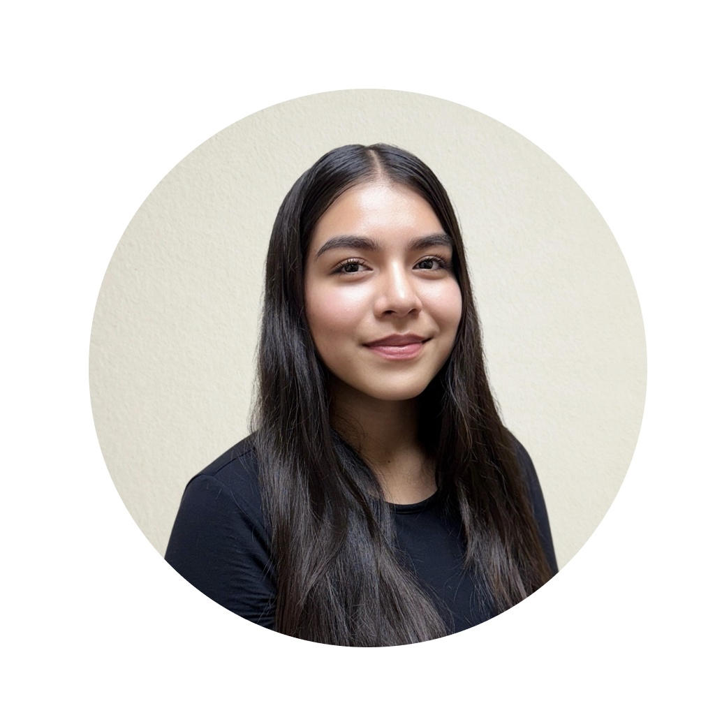 The image is a circular headshot of a person with long hair, wearing a dark top, posing against a plain background.