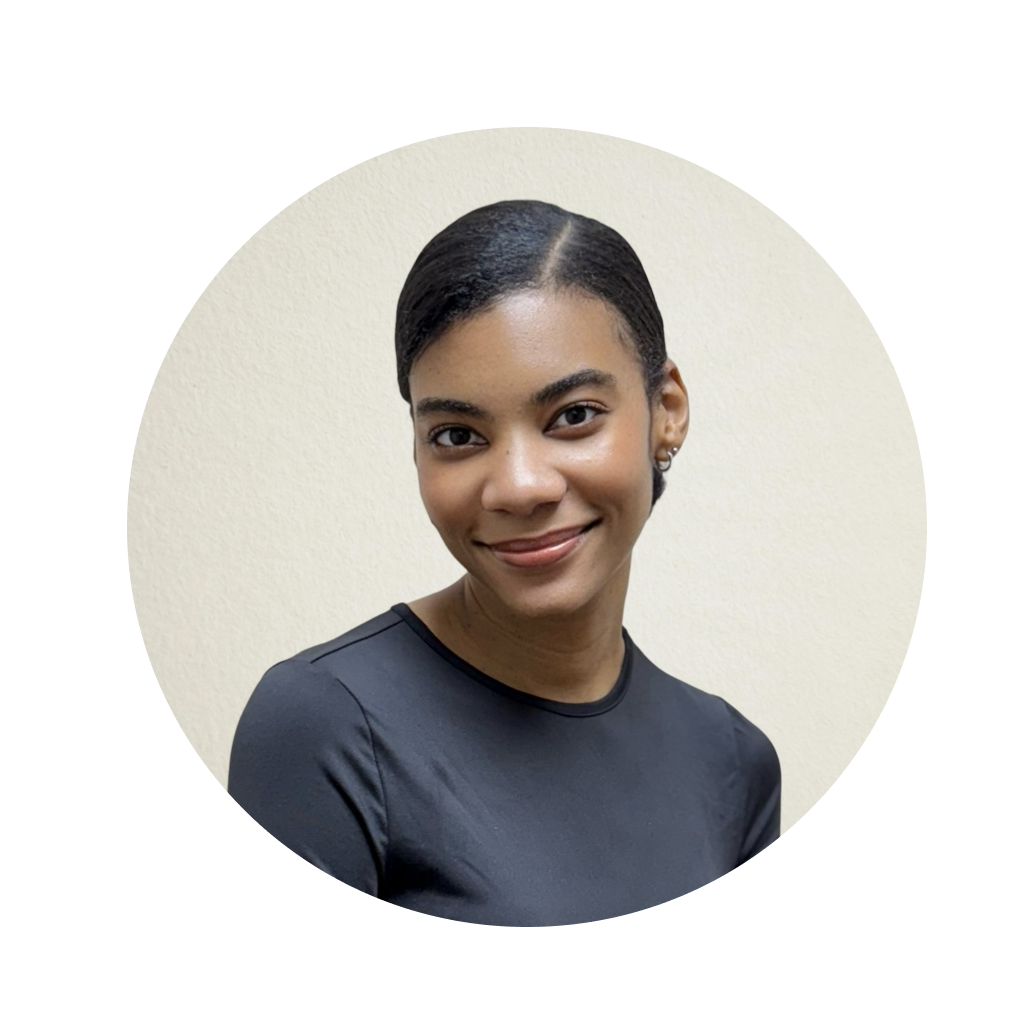 The image features a woman with short hair, wearing a dark top and a small earring. She has a neutral expression on her face and is looking directly at the camera.