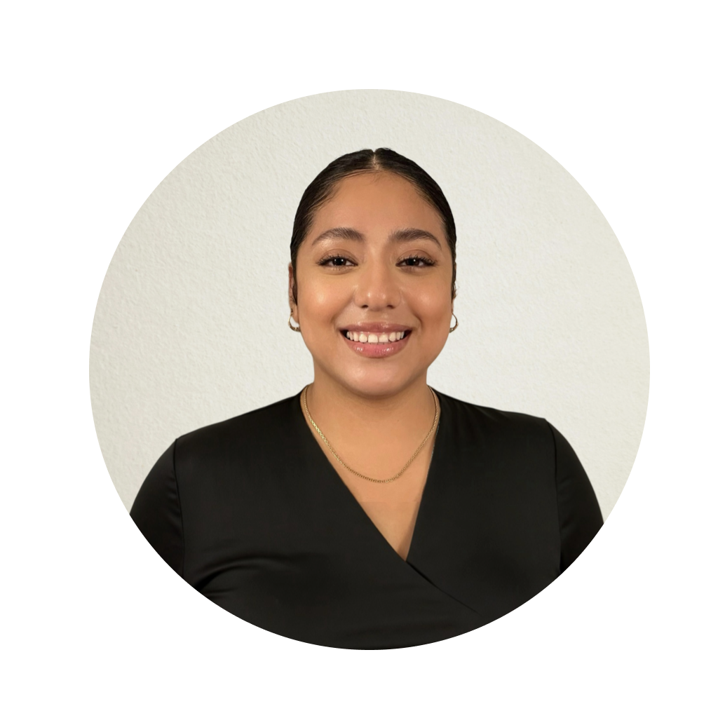 The image is a circular headshot of a smiling woman with dark hair, wearing a black top, standing against a white background.